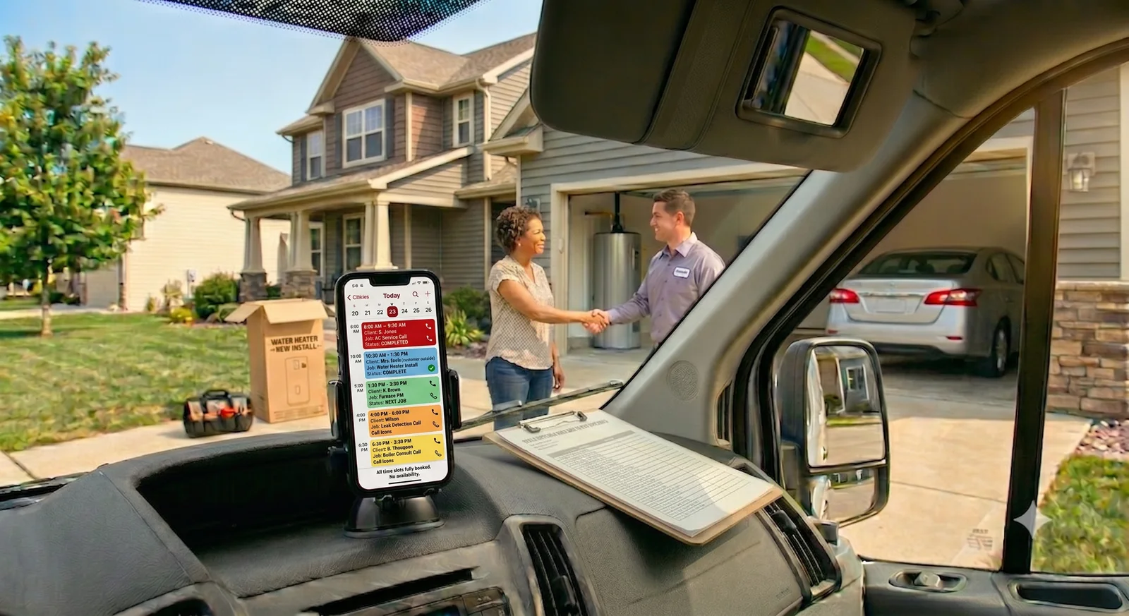 Tradesperson in work van with fully booked schedule, completing a job at a customer's home